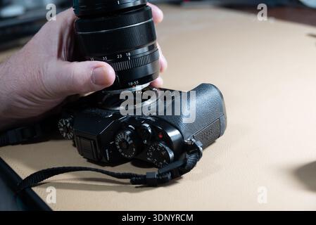 Mit der Hand wird ein Objektiv an einer Digitalkamera befestigt, um die Aufnahme von Bildern vorzubereiten. Stockfoto