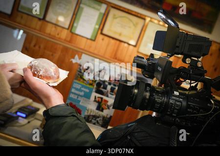 Warschau, Polen. Februar 2026. Ein Kamerabediener filmt am 12. Februar 2026 in der legendären Bäckerei Zagozdzinski in Warschau, Polen, ein „Paczki“ oder Donut. Jedes Jahr am letzten Donnerstag vor der Fastenzeit stehen die Polen in langen Warteschlangen, um Donuts zu kaufen, eine Tradition des Festens vor dem Fasten zu Ostern. (Foto: Jaap Arriens/SIPA USA) Credit: SIPA USA/Alamy Live News Stockfoto