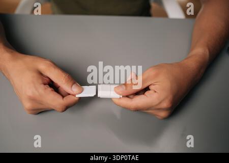 Nahaufnahme der männlichen Hände, die eine microsd-Karte mit einem usb-Adapter verbinden, erleichtert die Datenübertragung oder erweitert die Speicherkapazität gegen Grau Stockfoto