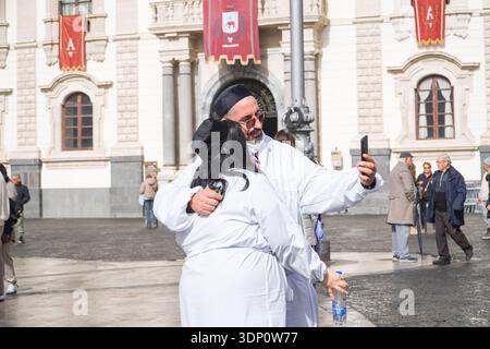 Gläubige in weißen Gewändern umarmen und machen ein Selfie während des Festes der Heiligen Agatha (Festa di Sant'Agata) auf der Piazza del Duomo, Catania, mit dem Palazz Stockfoto