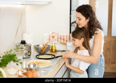 Mom und ihre Tochter braten Pfannkuchen Stockfoto