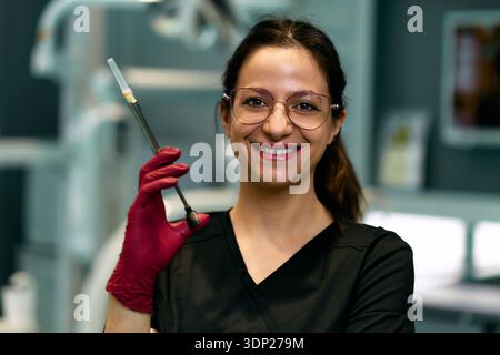 Lächelnde Weibliche Medizinische Fachkraft, Die Spritze In Klinischer Umgebung Hält Porträt Mit Brille Stockfoto