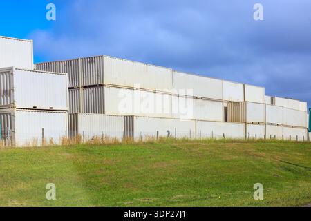 Die gestapelten Frachtcontainer befinden sich im belebten Bereich mit dem Logistikzentrum Stockfoto