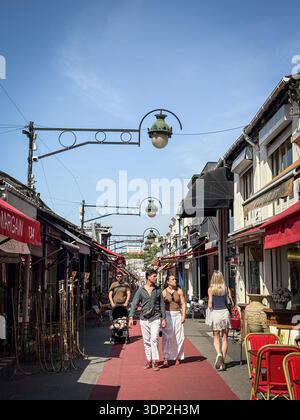 PARIS, FRANKREICH - 22. JUNI 2025: Besucher spazieren durch die Marche Biron auf dem Flohmarkt Puces de Saint-Ouen in Paris, Frankreich. Roter Teppich Gang, antike Straße Stockfoto