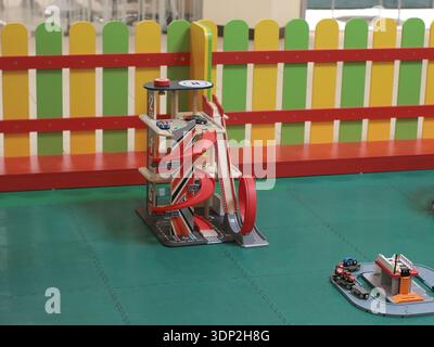 Spielzeugzug aus Holz mit Gleisen, Gebäuden und Fahrzeugen, die auf einem Spieltisch im Haus angeordnet sind. Bunte Spielzimmer-Szene, Kinderaktivitäten, Spielzeugkataloge, Stockfoto