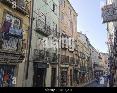 Blick auf eine Straße mit bunten Gebäuden, Wäscherei hängt auf schmiedeeisernen Balkonen in Lissabon, Altstadt, Lissabon, Portugal Stockfoto