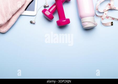 Fitness-Konzept flach auf blauem Hintergrund mit Sneakers, Hanteln und Maßband, rosa Handtuch und Wasserflasche, flach Ley Kopierraum Stockfoto