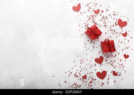 Rote kleine Geschenksets roten Herzen und confetty auf grauem Stein, festlich romantische Karte Vorlage Stockfoto