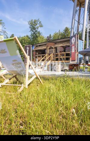 Ein Liegestuhl auf einem Rasen mit Blick auf eine Holzkonstruktion bei hellem Sonnenschein Stockfoto