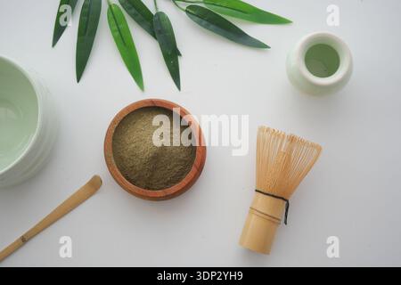 Matcha-Vorbereitungswerkzeuge auf einem Tisch mit grünen Blättern Stockfoto
