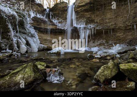 Ein kleiner Wasserfall mit gefrorenen Eiszapfen ergießt sich in einen von Felsen umgebenen Bach, Mattenhof, Illighausen, Bodensee, Thurgau, Schweiz Stockfoto