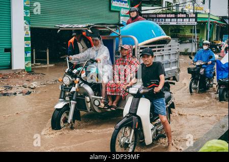 Eine Straßenszene, in der Menschen Motorräder auf einer überfluteten Straße bei starkem Regen in Nha Trang fahren. Nha Trang, Vietnam - 21. November 2025. Stockfoto