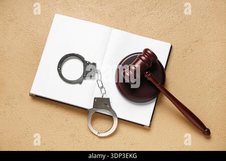 Hammer, Buch und Handschellen des Richters auf beigefarbenem Hintergrund Stockfoto