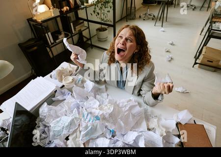 Junge Frau mit Stress während der Arbeit im Büro Stockfoto