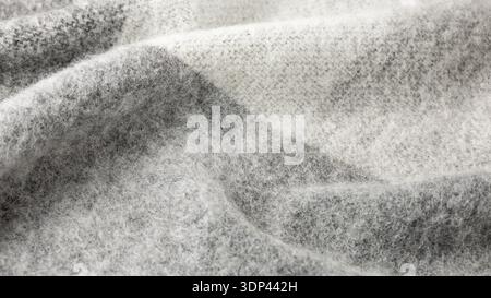 Weicher, warmer Schal aus Alpakawolle, Hintergrund mit Muster. Trendige cremegraue Wolltextur in Nahaufnahme. Stockfoto