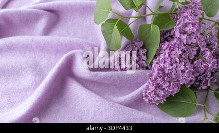 Fliederzweig mit Aromablüten auf weichem reinem Kaschmir. Natürlicher lilafarbener Cashmere Hintergrund und Blumen mit Kopierraum. Stockfoto