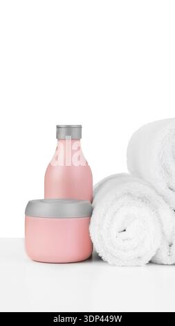 Spa-Einrichtung mit rosafarbenen Behältern und weißen Handtüchern auf einer sauberen Oberfläche Stockfoto
