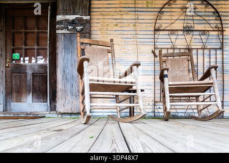Zwei hölzerne Schaukelstühle auf einer rustikalen Veranda wecken ein Gefühl von Nostalgie und Ruhe. Stockfoto