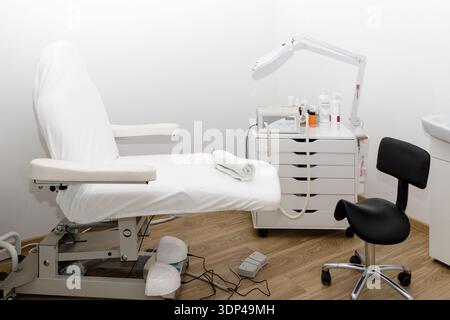 Das Innere eines Raumes zur professionellen Fuß- und Nagelbehandlung und -Pflege. Weißer Sessel und Geräte Stockfoto