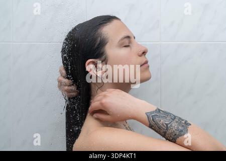 Frau genießt die Dusche, die Haare mit geschlossenen Augen wäscht Stockfoto