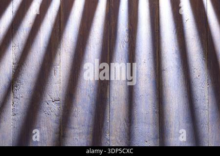 Blaue graue Holzdielen mit dramatischen diagonalen Schatten. Rhythmisches Licht- und Schattenspiel auf Holzoberfläche Stockfoto