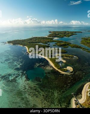 Aus der Vogelperspektive auf das ruhige türkisfarbene Wasser, das die grüne Küste umschließt und versteckte Lagunen und Sandflächen enthüllt, Shangri La, Trou d'Eau Douce Stockfoto