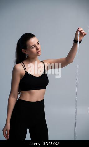 Eine Frau, die steht und ein Maßband in der Hand hält Stockfoto
