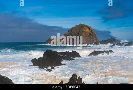Großer vulkanischer Felsen mit Leuchtturm im schäumenden Ozean. Stockfoto