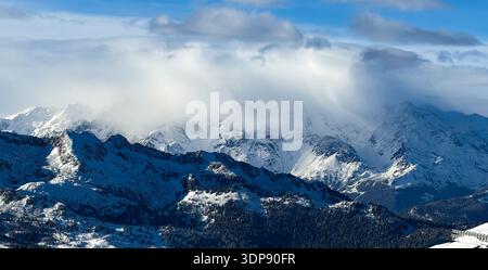 Dramatische schneebedeckte Bergkette mit mächtigen Sturmwolken über Gipfel, Winterlandschaft in den italienischen Alpen. Stockfoto