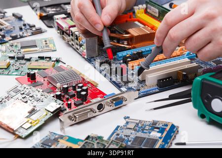 Ingenieur überprüft die Hauptplatine mit einem Multimeter Stockfoto