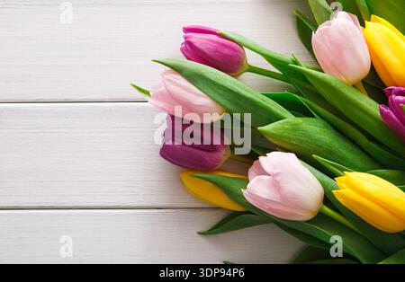 Farbenfrohe Tulpen auf einer hellen Holzoberfläche in einer kreativen Präsentation während der Frühlingssaison Stockfoto
