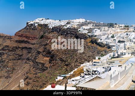Panoramablick auf die berühmten weiß getünchten Gebäude von Fira, Santorin, Griechenland, die auf der vulkanischen Caldera-Klippe unter einem klaren blauen Himmel thronen. Stockfoto