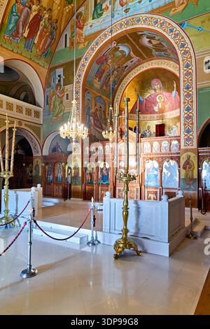 Das Innere einer lebhaften griechisch-orthodoxen Kirche in Santorin, die mit aufwendigen Fresken und einer kunstvollen Ikonostase geschmückt ist und als Gotteshaus dient Stockfoto