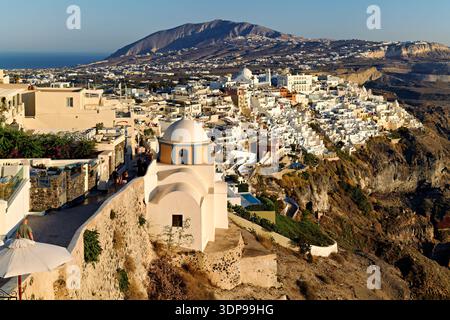 Touristen erkunden die malerische Stadt Fira, Santorini, Griechenland, mit ihren berühmten weißen Gebäuden und Kirchen mit blauer Kuppel und genießen die Betäubung Stockfoto