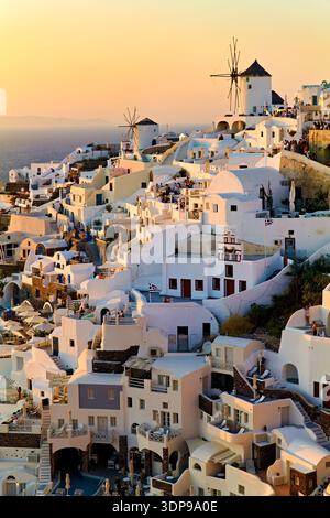 Touristen treffen sich in Oia, Santorin, Griechenland, um den atemberaubenden Sonnenuntergang über der Ägäis zu erleben, umgeben von berühmten weiß getünchten Gebäuden und gewinnen Stockfoto