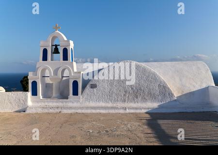 Weiße griechisch-orthodoxe Kirche mit einem Glockenturm und blauen Akzenten mit Blick auf die Ägäis in Griechenland. Ein Schild erinnert die Besucher daran, nicht auf das Heilige zu klettern Stockfoto