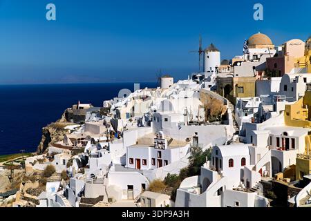 Oia, Santorini, Griechenland. Die berühmten weiß getünchten Gebäude und Windmühlen dieses Klippendorfes überblicken die tiefblaue Ägäis, ein beliebter Tourist Stockfoto