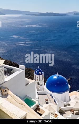 Atemberaubende Aussicht auf die Caldera von einem Dorf an den Klippen in Santorin, Griechenland, mit ikonischer weißer Architektur der Kykladen und lebendiger, blauer Kuppel Stockfoto