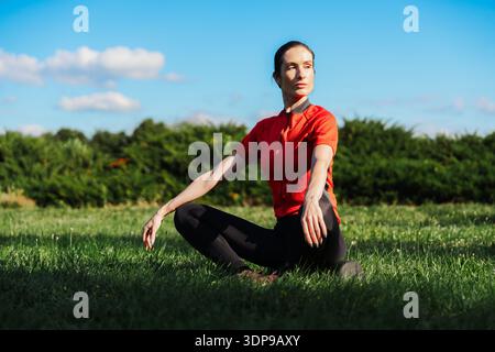 Frau übt Yoga auf Gras bei hellem Sonnenlicht Stockfoto