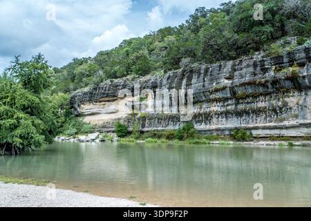 Ein Fluss fließt durch einen felsigen Canyon. Das Wasser ist klar und ruhig. Die Umgebung ist üppig und grün Stockfoto