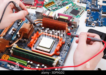Ingenieur überprüft die Hauptplatine mit einem Multimeter Stockfoto