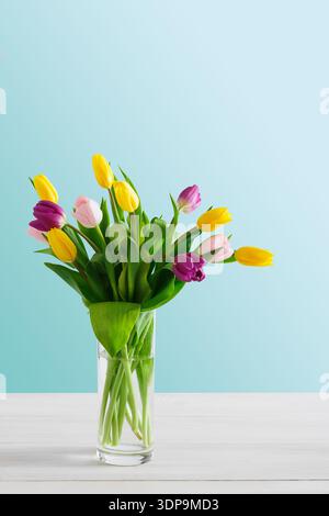Bunte Tulpen in einer Glasvase auf hellem Hintergrund in einem hellen Raum Stockfoto