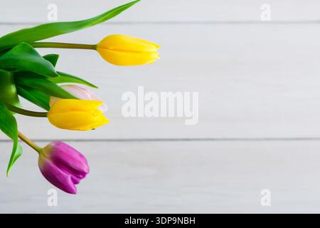 Bunte Tulpen in einer einfachen Vase auf einer Holzoberfläche in hellem Licht Stockfoto