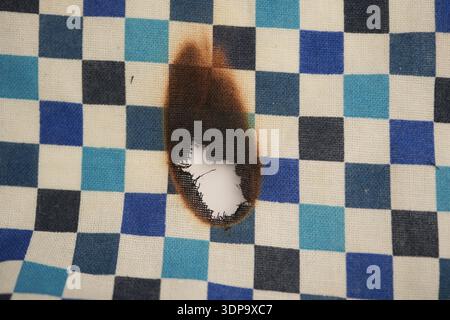 Brandflecken auf kariertem Tuch auf einem Tisch Stockfoto