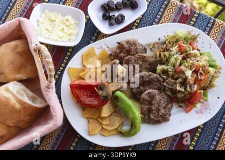 Typisch türkisches Kofte-Gericht mit grünem Pfeffer, Pilzen, Salat und Pommes frites Stockfoto