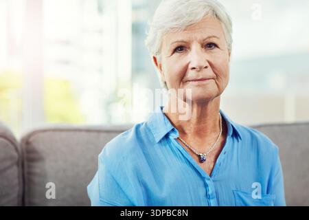 Porträt, ruhige und ältere Frau auf Couch zu Hause, Entspannung und positive Einstellung für Ruhestand Wellness. Wochenendfriedlichkeit, Ruhe und Seniorin Stockfoto
