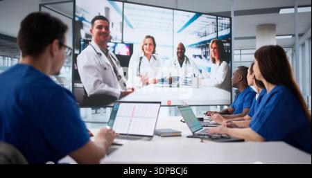Ärzte, Die Am Webinar Zum Projektorbildschirm Im Konferenzraum Des Krankenhauses Teilnehmen. Stockfoto