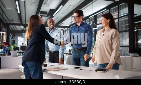 Erfolgreiche Frau, Die Das Arbeitsgespräch Verlässt, Schüttelt Sich Die Hand Mit Diverser Gruppe. Stockfoto