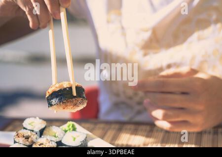 Frau mit Japan sticks isst Sushi in Street Cafe Stockfoto