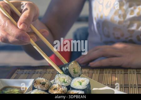 Frau mit Japan sticks isst Sushi in Street Cafe Stockfoto